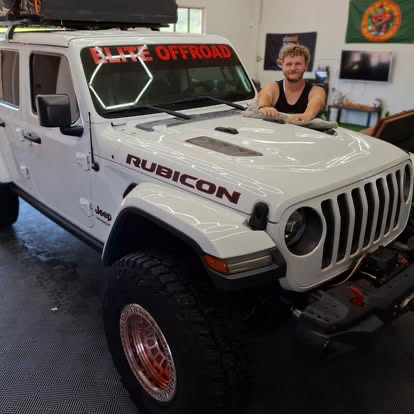 White Jeep Wrangler Rubicon with Elite Offroad windshield banner in the shop bay