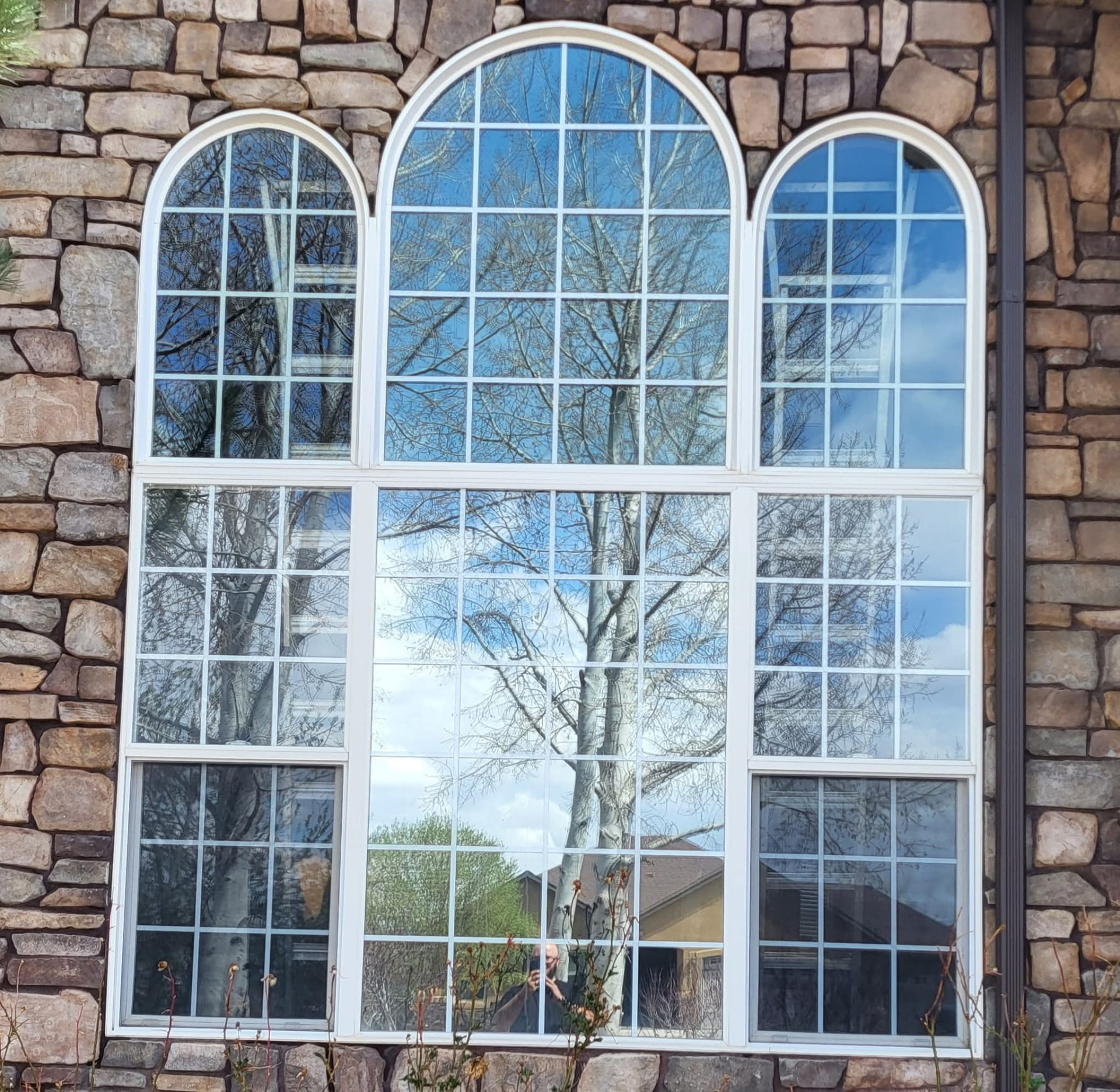 Tall arched stone-front home windows, clean and glare-free after service